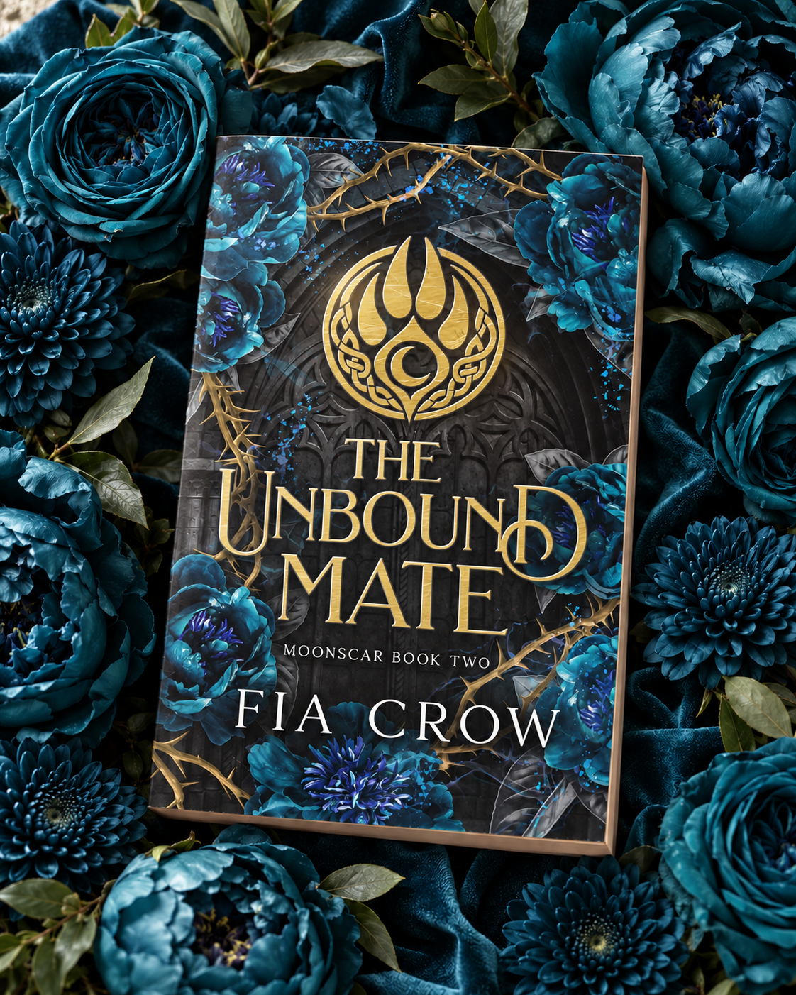 The Unbound Mate paperback nestled in a lush bed of teal florist flowers on velvet